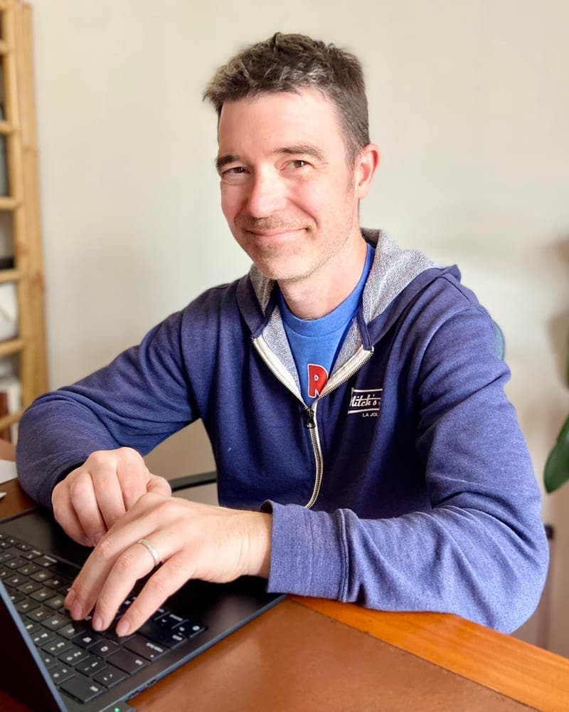 Kyle at his laptop, smiling at the camera